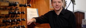 David Goode sits at the organ, looking at the camera